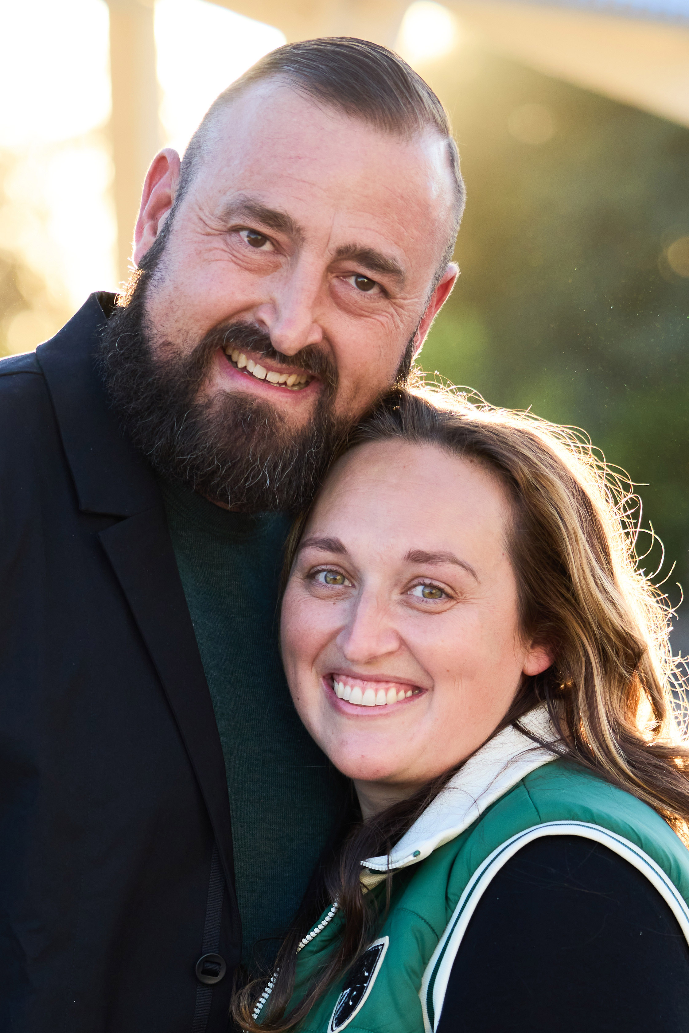 Takashi Sato and his wife smiling together in warm sunset light.