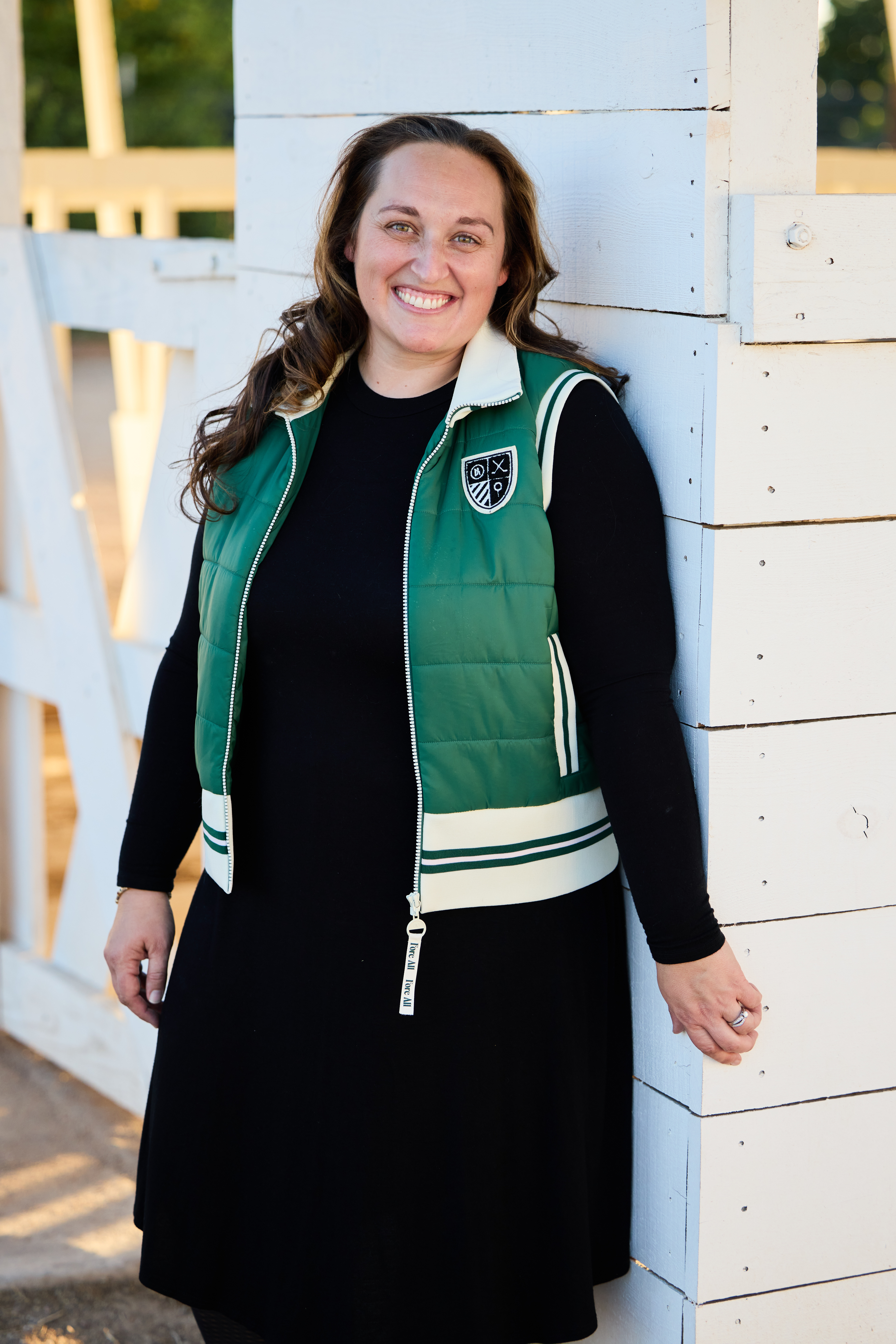 Smiling portrait of mom leaning against the white barn structure.