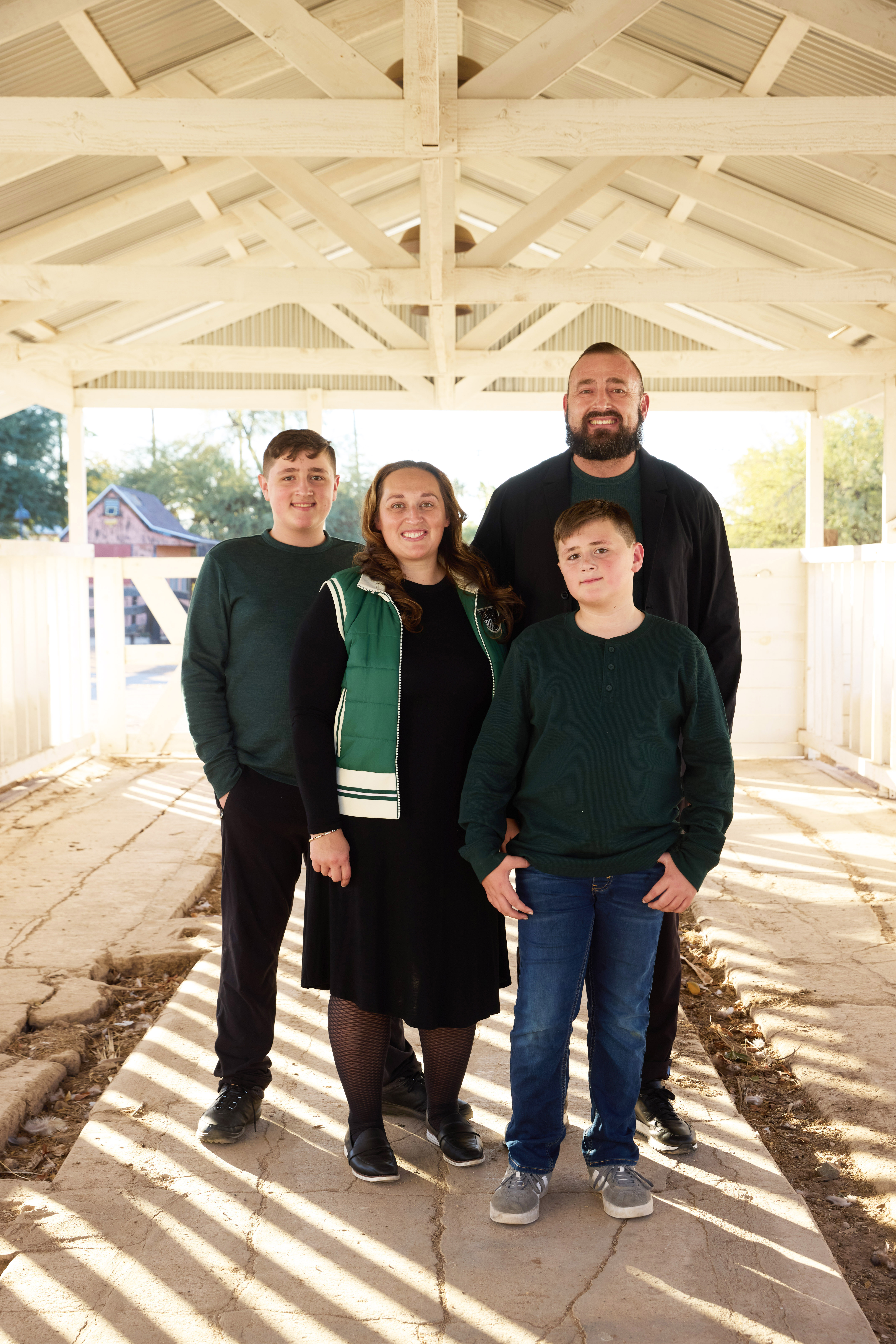 Family portrait under the sunlit barn walkway at Sahuaro Ranch Park.